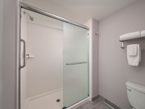 A bathroom with a glass shower enclosure, a white toilet, and a towel rack with two towels. - Homewood Suites Lancaster (Lancaster)