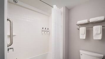 Un baño moderno con una bañera blanca, inodoro y zona de ducha.