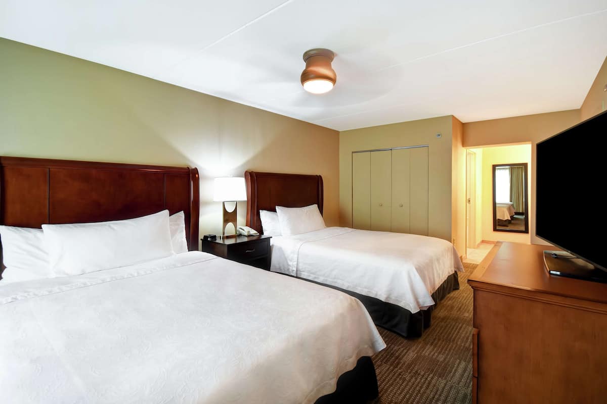 A hotel room with two beds, a desk, a television, and a wardrobe.