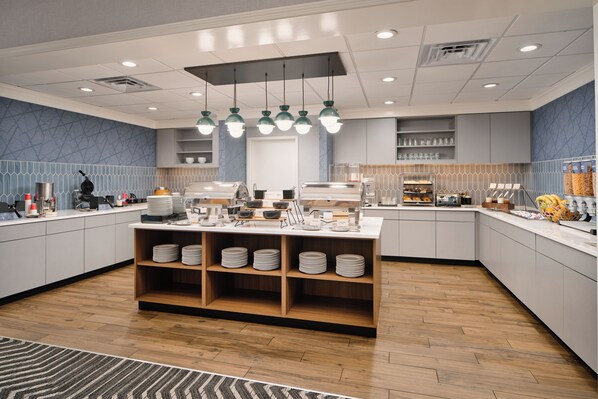 A modern kitchen with a central island, wooden shelves, and overhead lighting.
