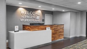 A reception desk with a "WELCOME TO THE PACIFIC WONDERLAND" sign, a "Hilton" sign, and a "HONORS" sign.