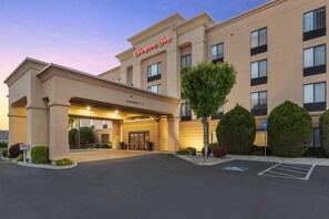A Hampton Inn hotel with a clear entrance, a parking lot, and a handicap parking sign.