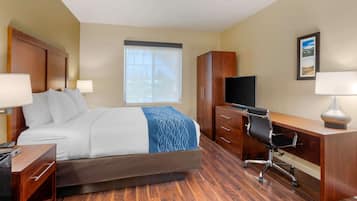A hotel room with a bed, a desk, a chair, a TV, and a window with blinds.