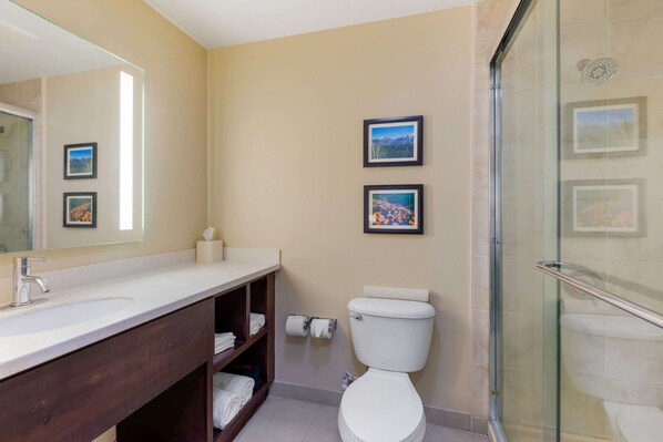 A bathroom with a white sink, a toilet, and a glass shower enclosure. There are two framed pictures on the wall. - Comfort Inn & Suites near Ontario Airport (Ontario)