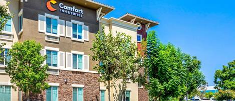 A Comfort Inn & Suites hotel with a modern facade, multiple windows, and a landscaped front yard.