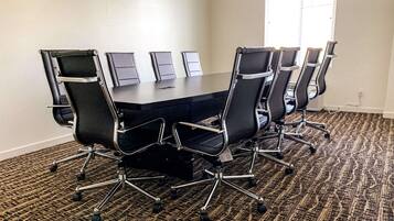 A conference room with a large table and six black office chairs with wheels.