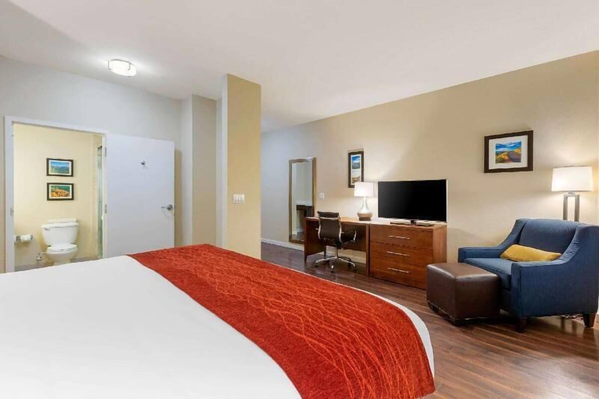 Une chambre d’hôtel comprenant un lit, un bureau, une chaise, une télévision et une salle de bain.