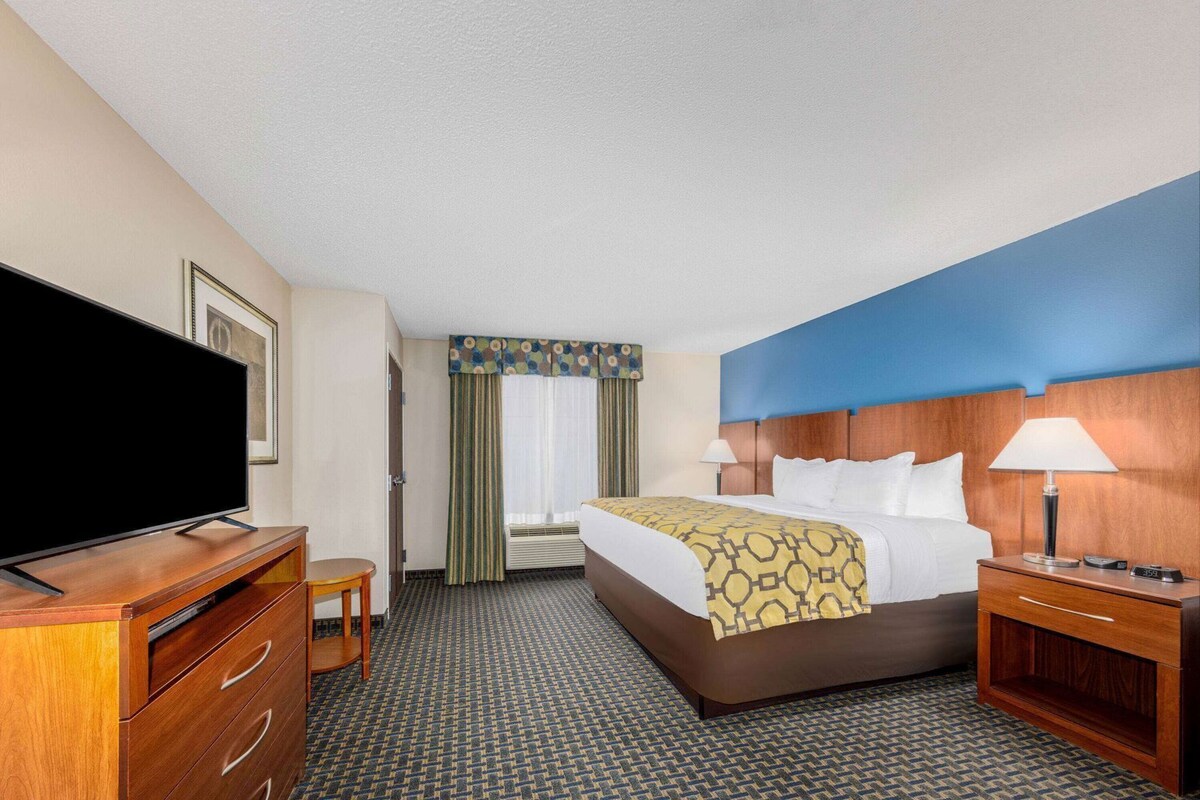 A hotel room with a bed, a TV, a desk, and a chair.