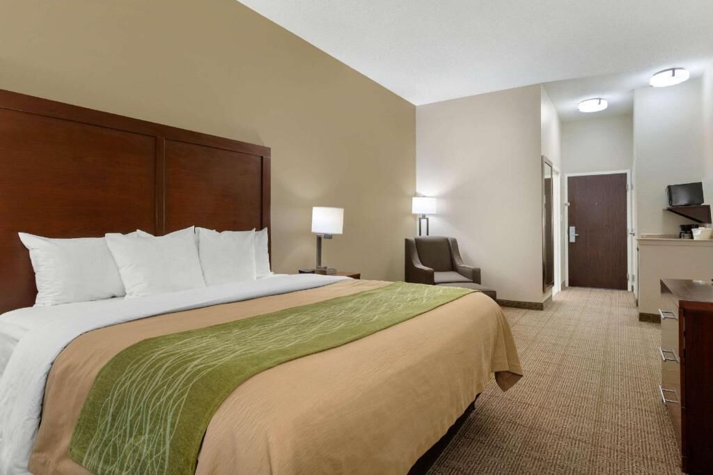 A hotel room with a large bed, a chair, a desk, and a television.