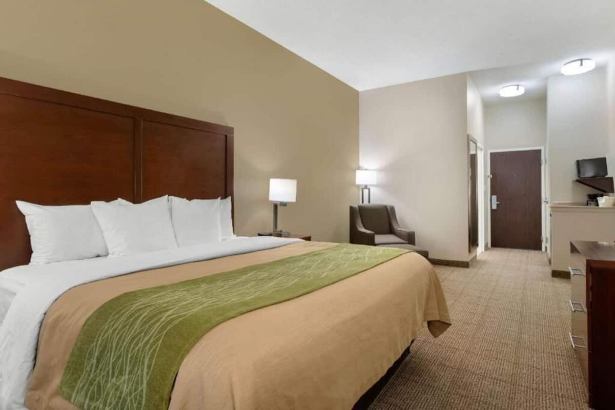 A hotel room with a large bed, a chair, a desk, and a television.