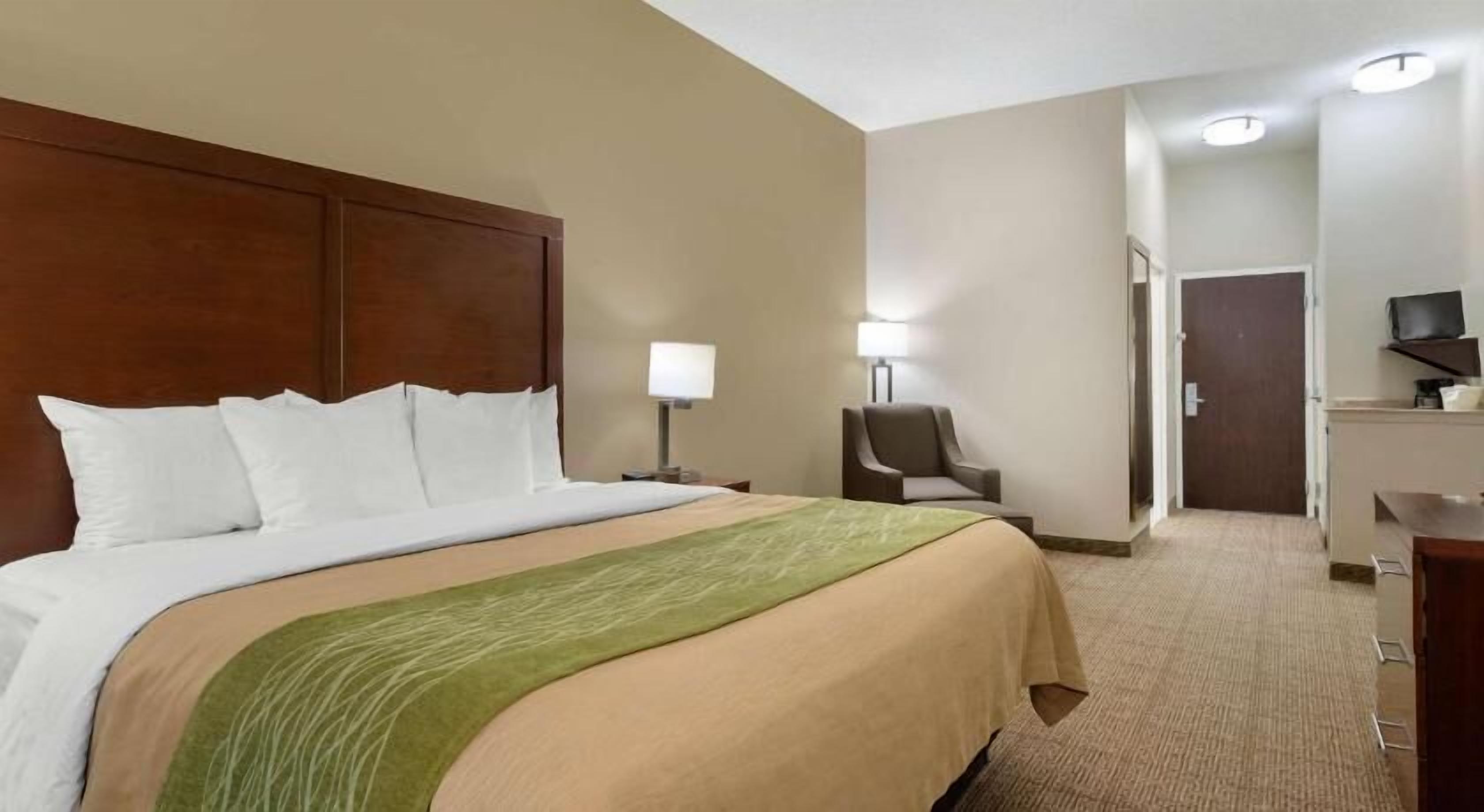 A hotel room with a large bed, a chair, a desk, and a television.