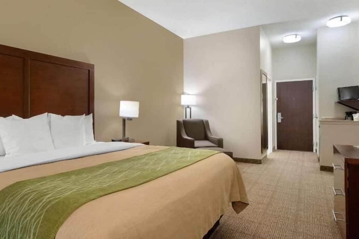 A hotel room with a large bed, a chair, a desk, and a television.