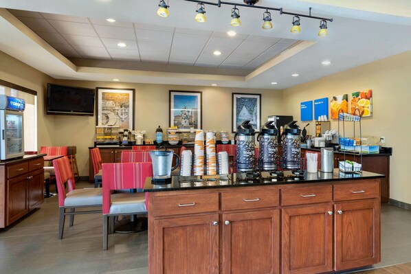 Un área de cocina moderna con una isla central, asientos tipo barra y una estación para café.