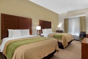 A hotel room with two beds, a desk, a chair, and a window with curtains.