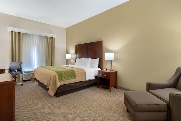 Ein Hotelzimmer mit Bett, Nachttischen, einem Sessel und einem Schreibtisch.