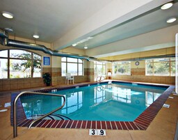 An indoor swimming pool with clear water, a diving board, and a lifeguard chair.