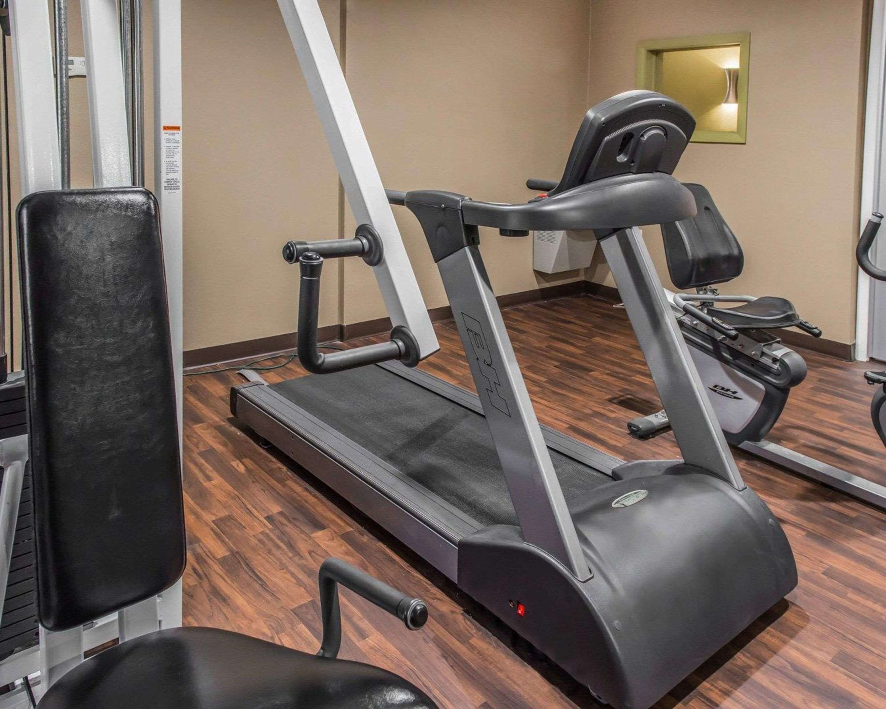 Un gimnasio con cinta de correr, bicicleta estática y banco para pesas.