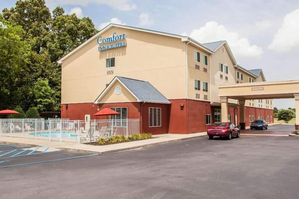A Comfort Inn & Suites hotel with a pool, a covered parking area, and a clear sky.