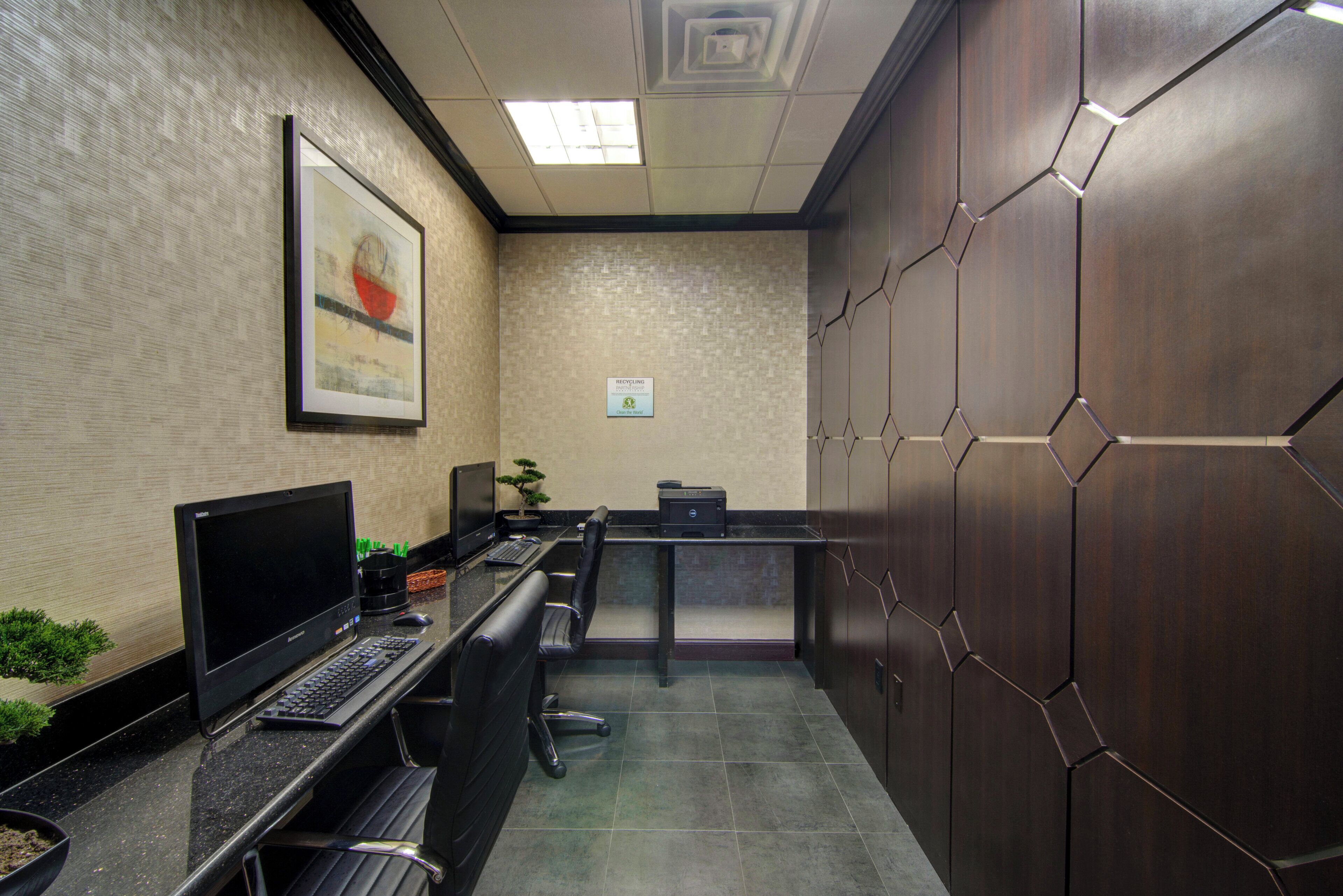 Un espace de bureau moderne avec un grand bureau, deux chaises, un ordinateur et une plante en pot.