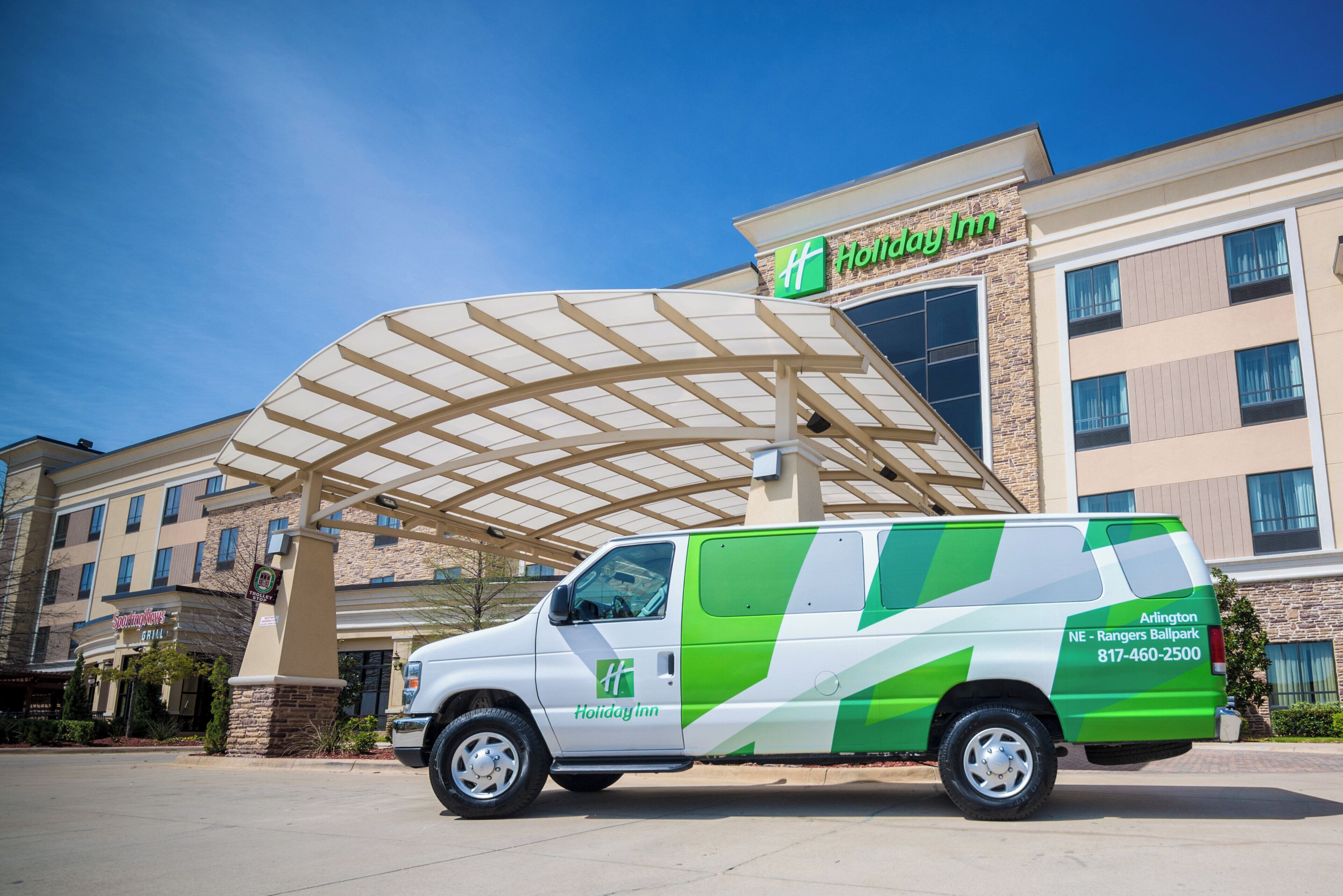 A Holiday Inn Express hotel with a covered entrance and a green and white service van parked in front.