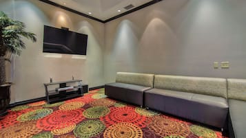 Una habitación con alfombra estampada, un televisor de pantalla plana montado en la pared, un sofá y una pequeña mesa con televisión.