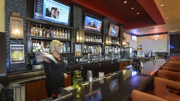 A bar area with multiple screens displaying news, a well-stocked bar, and a Texan-themed sign.