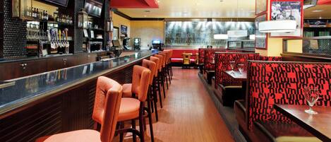 A bar area with a long counter, multiple TVs, and a variety of bottles.