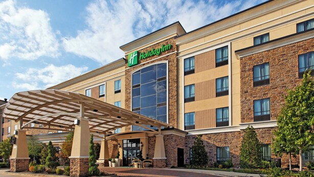 A Holiday Inn hotel with a covered entrance, large windows, and a stone facade.