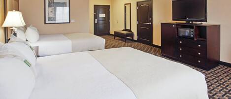 A hotel room with two beds, a television, a desk with a computer, and a mirror.