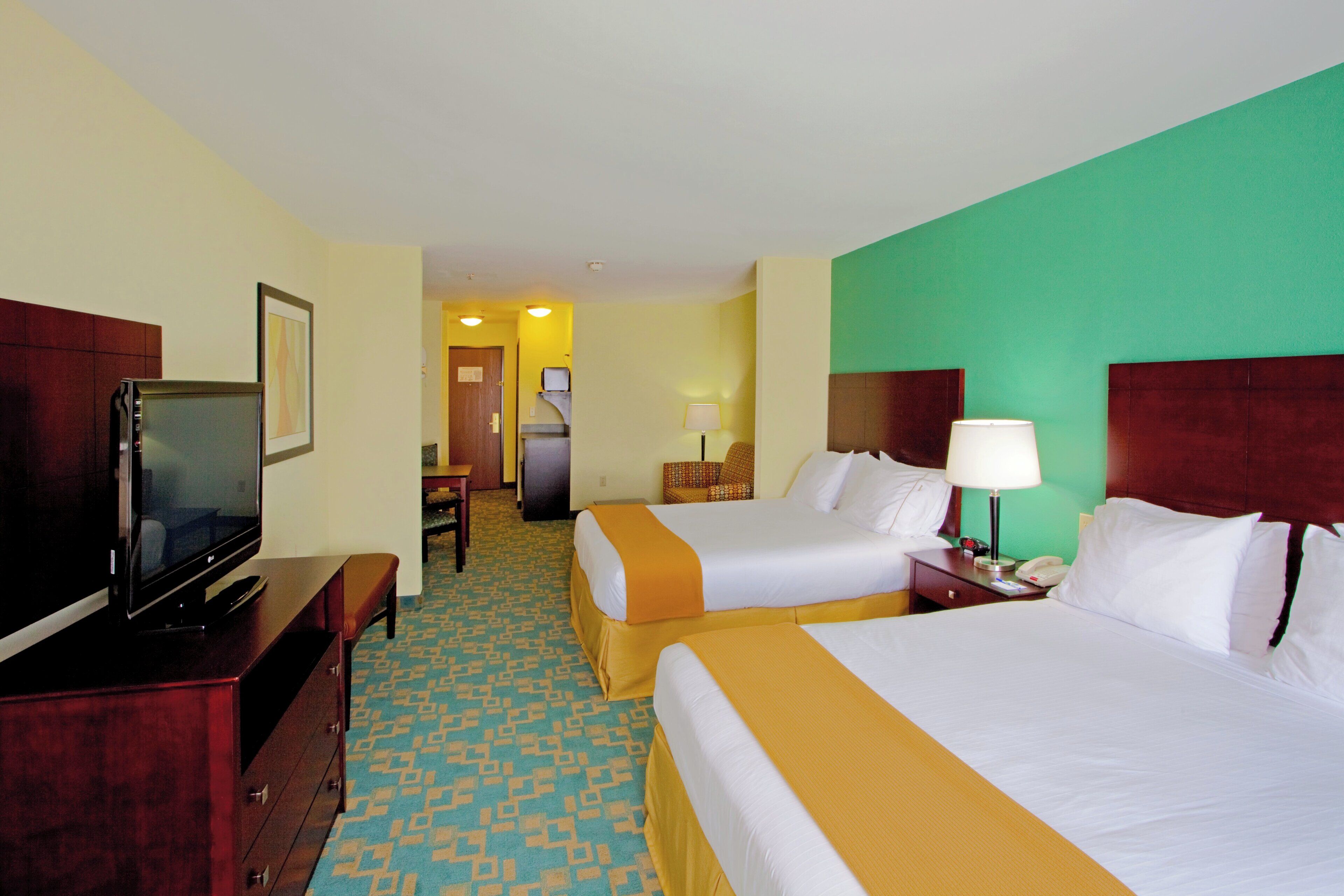 Een hotelkamer met twee bedden, een televisie, een bureau en een stoel.