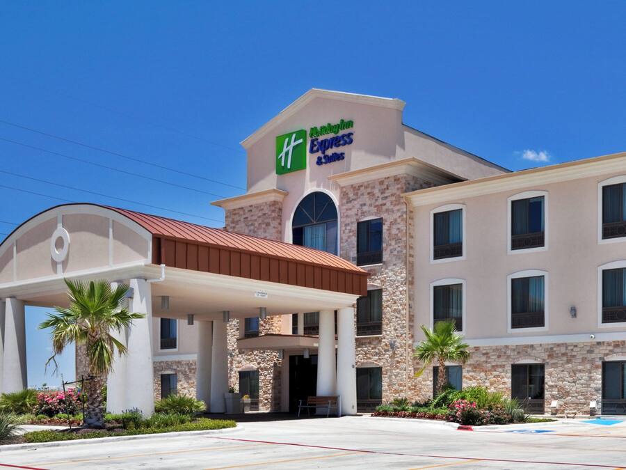 Een hotel met een heldere ingang, een overdekt gebied en een bord waarop staat dat het een Holiday Inn Express & Suites is.