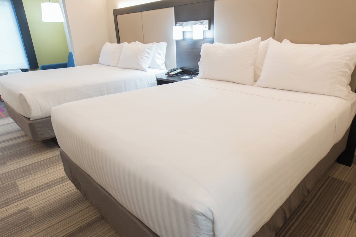 Twin beds with white linens, a bedside table with a phone, and a headboard with a mirror.