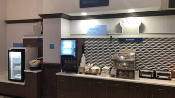 A breakfast area with a sign for 'Express Start Breakfast', a beverage dispenser, a bakery section, and a refrigerator with a yogurt display.