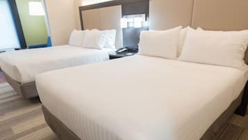 A hotel room with two single beds, a nightstand with a phone, and a large mirror above the beds.