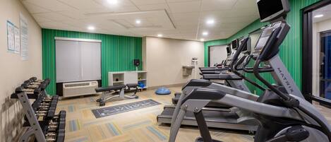 Een fitnessruimte met loopbanden, hometrainers en losse gewichten.