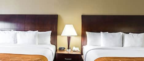 Una habitación de hotel con dos camas, una mesita de noche con lámpara y un teléfono.