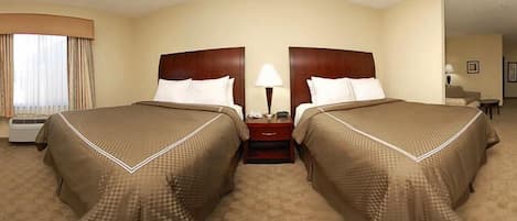A hotel room with two beds, a nightstand with a lamp, and a window with curtains.