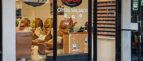A crystal nail salon with a neon 'Open' sign, a reception desk, and a display of nail polish bottles.