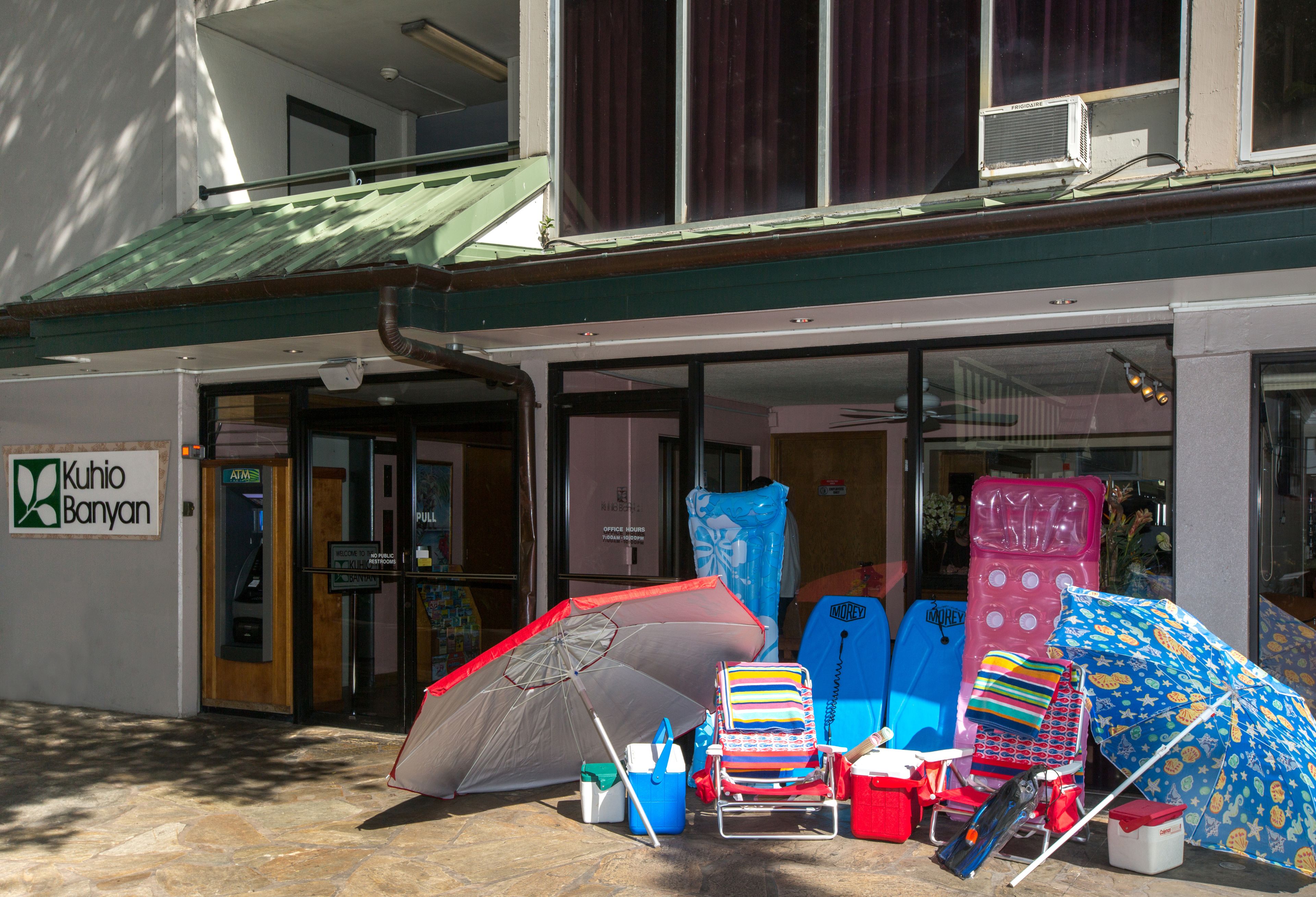 A building with a sign reading "Kuhiro Banyan" and a variety of beach chairs and umbrellas outside.