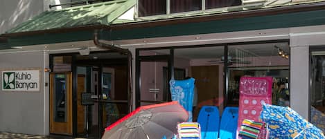 A building with a sign reading "Kuhiro Banyan" and a variety of beach chairs and umbrellas outside.