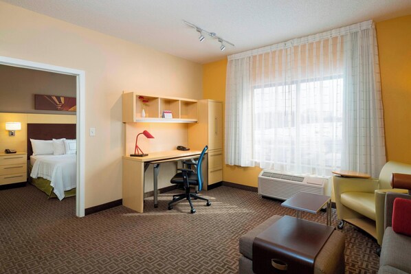 Une chambre d’hôtel avec un lit, un bureau, une chaise et une petite table.