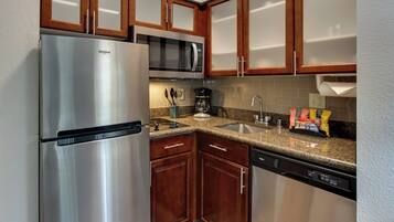A kitchen with stainless steel appliances, wooden cabinets, granite countertops, and a dishwasher.