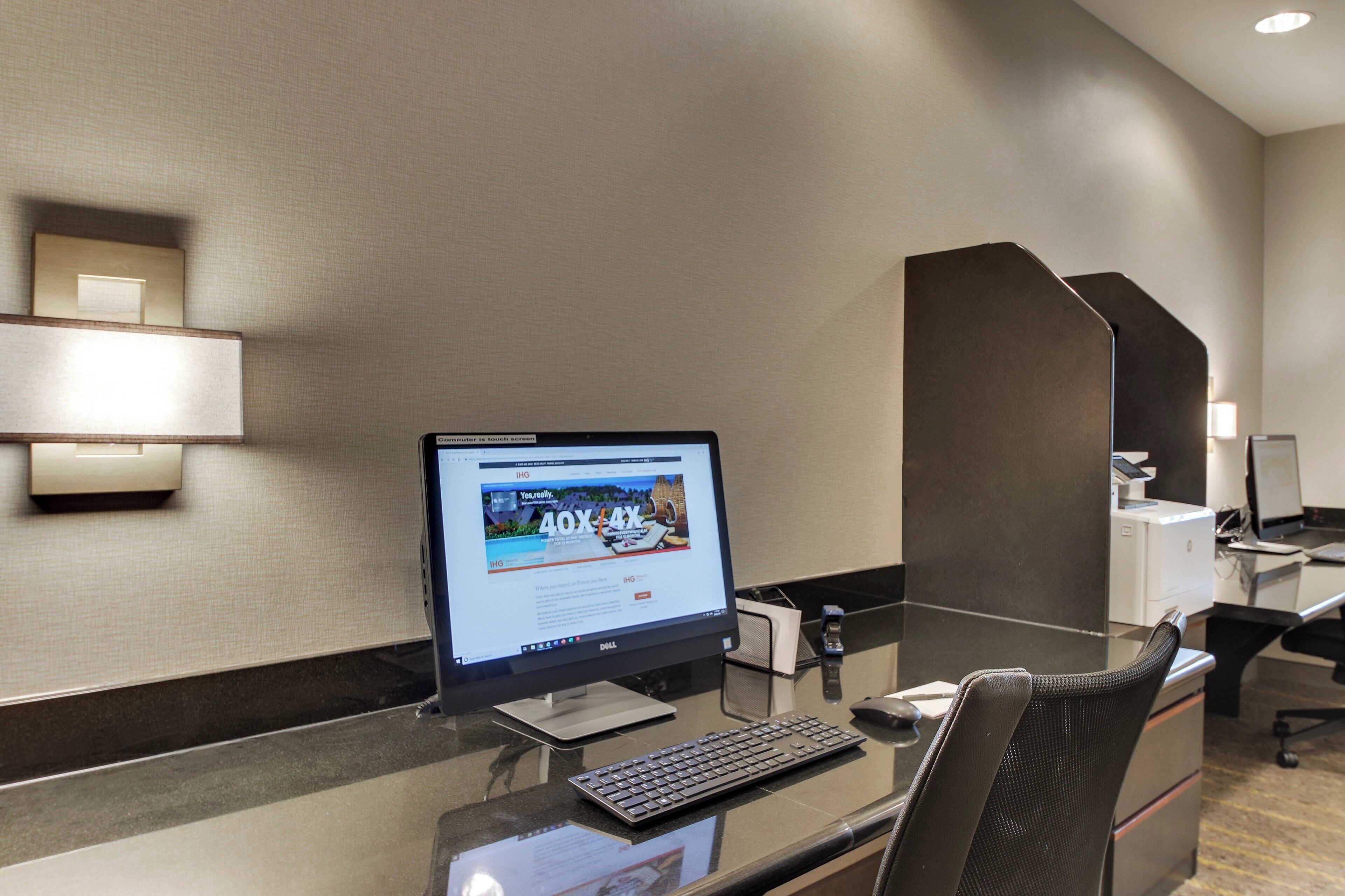 A hotel reception desk with a computer, a keyboard, and a chair.