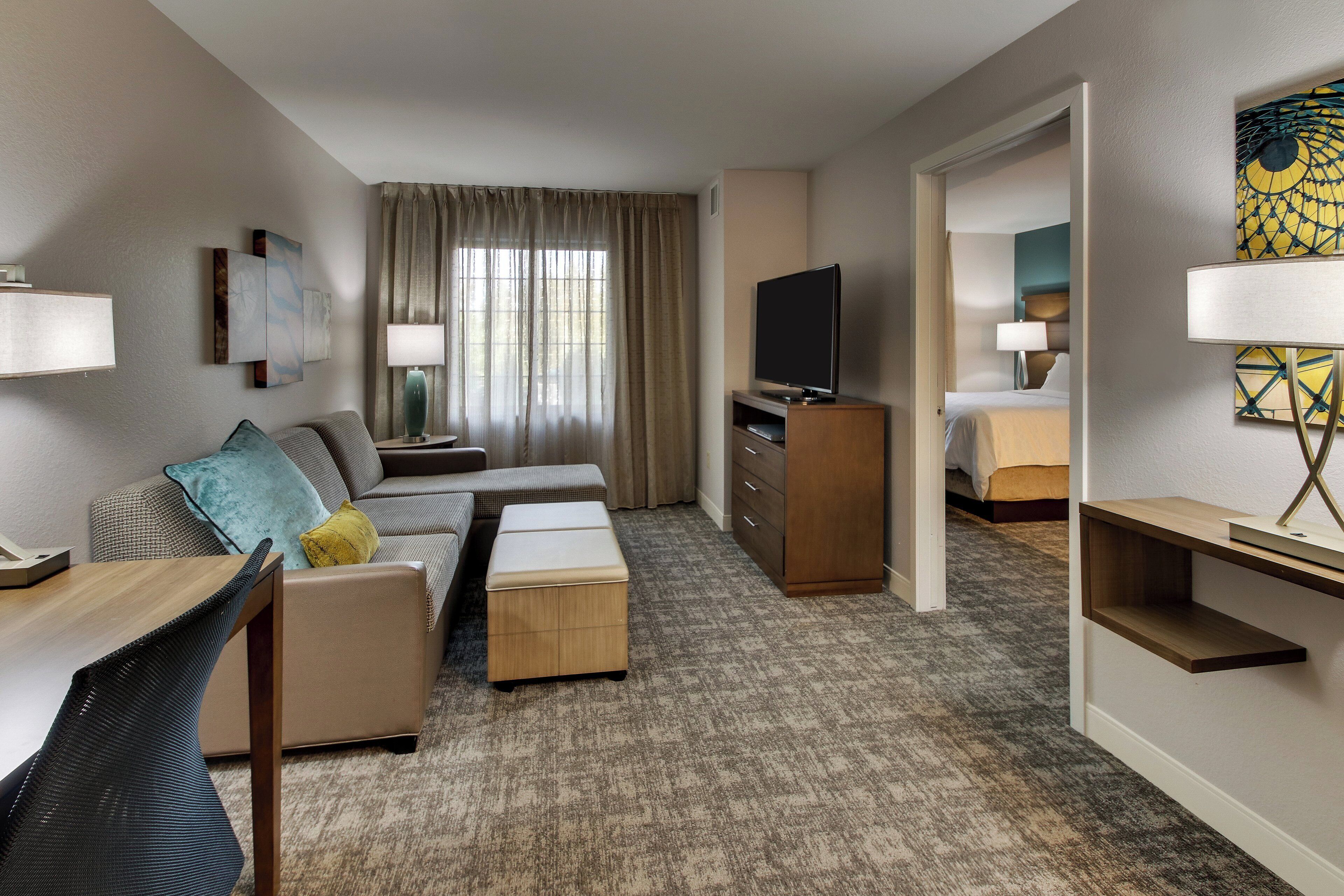 Una habitación de hotel con sofá, televisor, escritorio y cama.