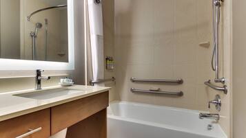A modern bathroom with a bathtub, a sink with a mirror, and a shower area.