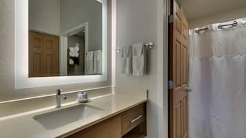 A bathroom with a sink, mirror, and shower curtain.