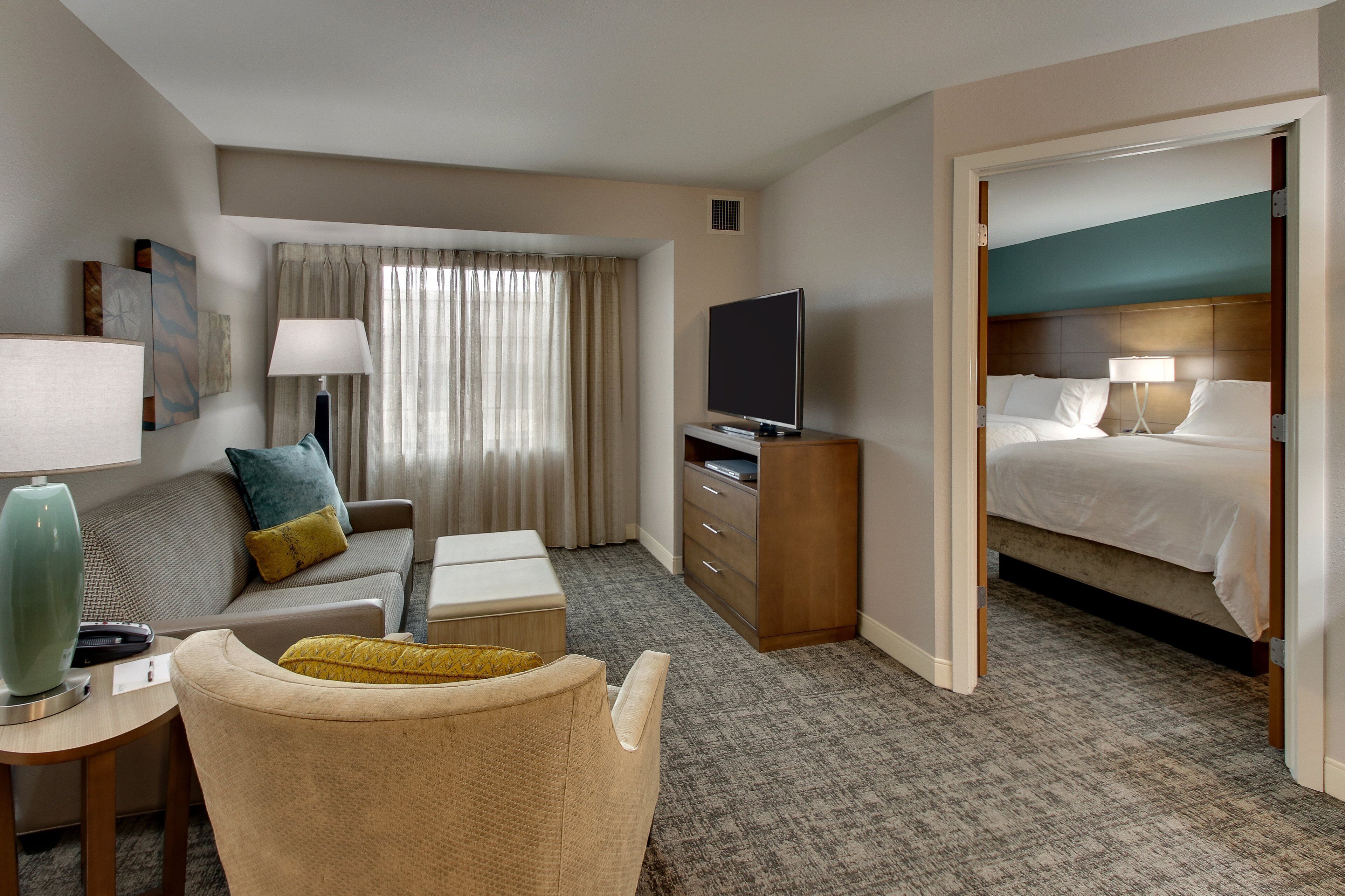 A hotel room with a bed, a TV, a sofa, a desk, and a chair.