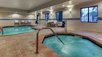 A hotel pool area with two pools, lounge chairs, and a sign indicating no diving.