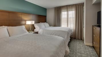 A hotel room with two beds, a nightstand with a lamp, a TV, and a wardrobe.