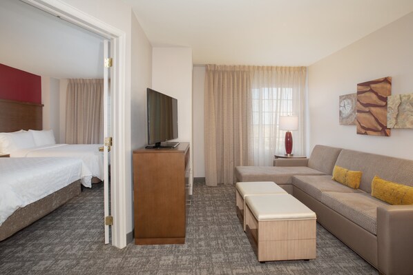 A hotel room with a bed, a sofa, a TV, and a desk. - Staybridge Suites Denver International Airport by IHG (Denver)